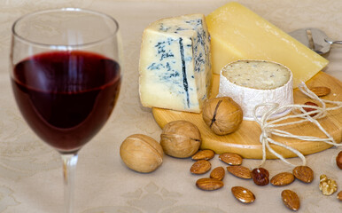 Cheese board with three types of cheese, nuts, and a glass of red wine. Cheese and red wine as cognitive decline prevention foods