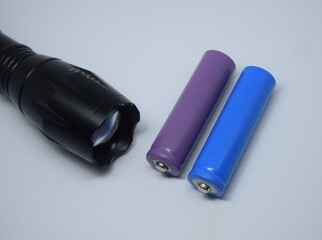 Two 18650 batteries lie next to the flashlight. Symbol of clean energy. Eco friendly