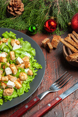 bottom view caesar salad on oval plate fork knife bowl with dried crust on dark red background