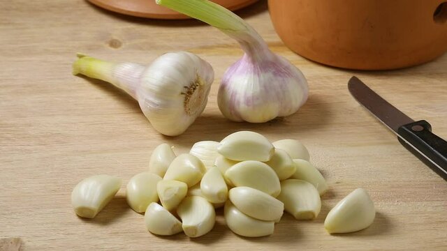  Heap of raw peeled garlic with fresh picked garlic in the background