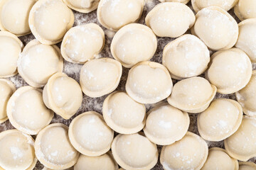 top view of many frozen Pelmeni (russian dumplings filled with minced meat) on wooden board
