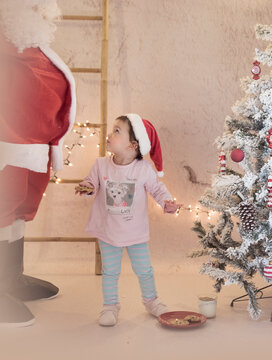 Ni&ntilde;a con Pap&aacute; Noel - Santa Claus con &aacute;rbol de navidad y gorro de Pap&aacute; Noel con pijama y galletas y leche