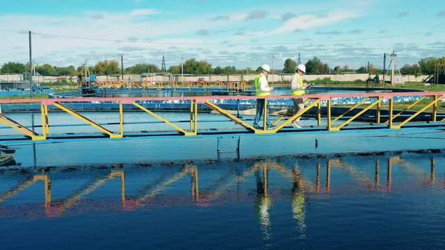 Drone Shot Of Wastewater Operators Examining A Water Clarifier. Sewage Treatment Concept.