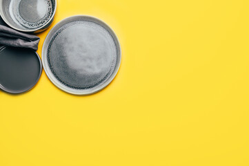 Different gray empty ceramic plates on yellow background, trendy colors 2021, Top View, Copy Space