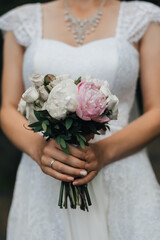 Obraz na płótnie Canvas wedding bouquet with pink peonies and white roses in the hands of the bride