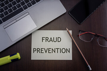 Fraud prevention card. Top view of office table desktop background with laptop, phone, glasses and pencil with card with inscription fraud prevention.  Security concept.