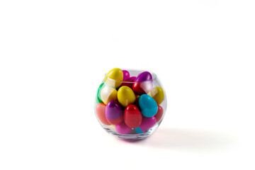 Colorful Plastic Easter Eggs in a glass vase on white background