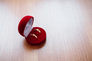 pair of gold wedding rings lie in a red box