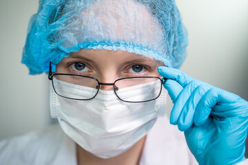 Young girl doctor looks at you with her glasses down