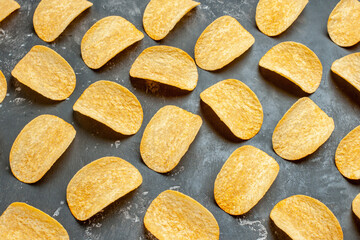 Top view of delicious homemade potato chips laid on gray background