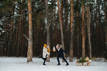 Young woman with child in her hands running to meet her husband in a majestic winter conifer...