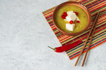 japanese or asian spicy miso soup with tofu and red pepper in a brown bowl on a stand with chopsticks horizontal photo with copy space