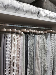 View of a wardrobe with woolen blankets hanging on hangers and pillows and blankets on the shelves.