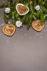 Border of Christmas tree branches and crocheted hearts on black stone concrete background