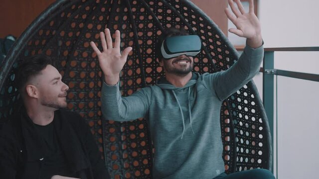 Amused gay couple testing the virtual reality glasses at home. High quality 4k footage