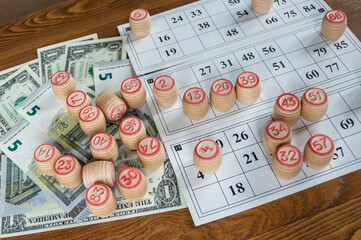 Bingo game (Russian Lotto): cards and barrels with numbers and paper bills on a wooden table.