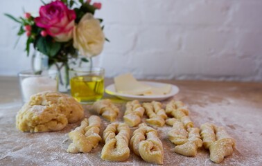 Making homemade cakes. Raw dough, butter, sugar, roses for making brushwood on a wooden tabletop. Concept on a white brick wall background. Homemade food during quarantine and lockdown.