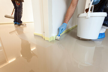 Close-up of construction workers applying a new layer of an indoor synthetic cast coating floor...