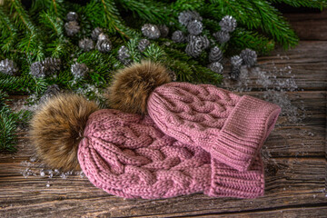 Fototapeta na wymiar Warm knitted pink hats with pompom for mother and daughter. Christmas decoration on wooden background.