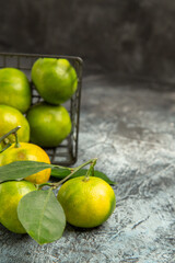 Fototapeta na wymiar Vertical view of fallen basket with fresh green tangerines on gray background