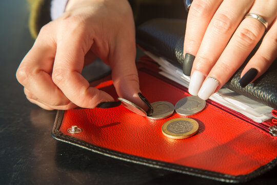 women's hands with a beautiful manicure take coins from a leather wallet. 