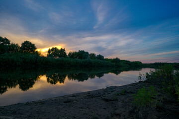 Summer landscape with the setting sun and clouds over the water.