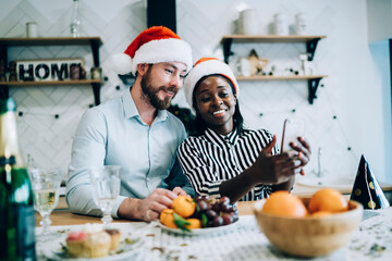 Smiling multiethnic adult couple taking selfie at New year party