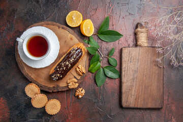 top view cup of tea with eclair and cookies on a dark background sweet biscuit cake