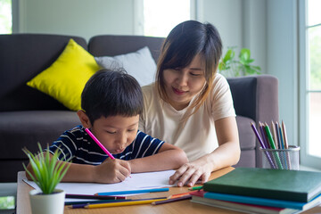 Mother helping son writing homework. Cute Asian mother helping your son doing your homework .