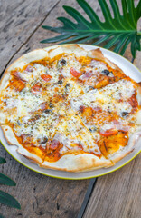 Homemade ham cheese pizza in a plate on a wooden table