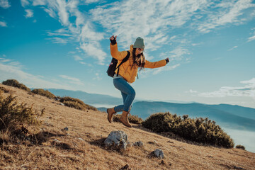 Cheering woman backpacker enjoy the view on sunrise mountain top cliff edge