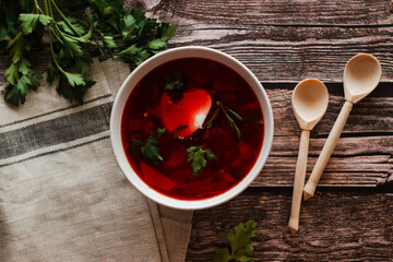 Borsch is a Russian national dish. Soup in a plate on a wooden table. Russian national cuisine. Borscht with sour cream and herbs