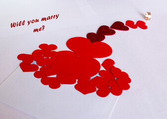 Many red hearts leading to the ring with a proposal to get married. A picture for Valentine's Day.