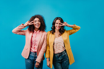 Fototapeta premium Two inspired girls having fun while shooting. Studio portrait of mixed race women.