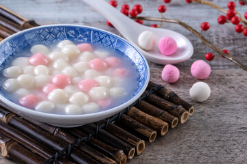 Close up of red and white tangyuan in blue bowl on wooden background for Winter solstice.