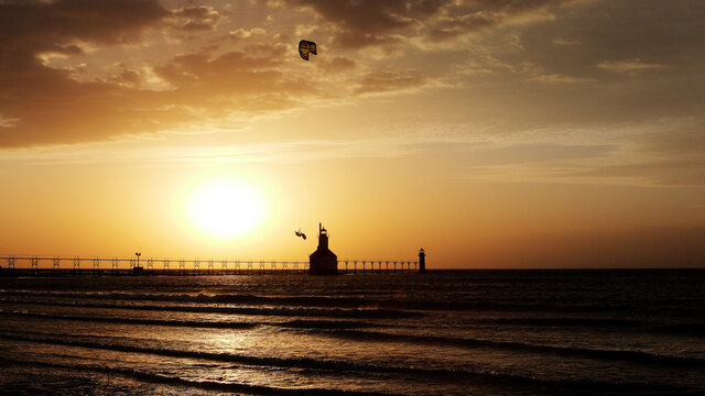 Kite boarder in the air at sunset by a lighthouse - Powered by Adobe