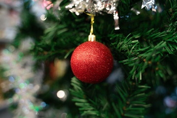 Obraz na płótnie Canvas Red ball hanging in a decorated Christmas tree. christmas and new year tree decoration. bokeh light. spruce, close up. 2021 