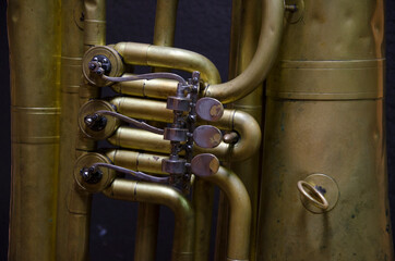 Musical wind instrument trumpet, tuba on the black background. Details and mechanism of the tuba....