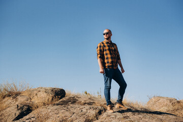 Fototapeta premium bald guy with a beard in jeans warm shirt and trekking shoes