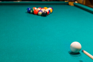 Sports game of billiards on a green cloth. Multi-colored billiard balls with numbers on a pool table