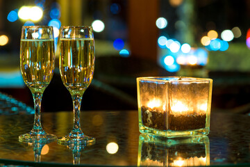 Two glass with champagne and burning candle on table