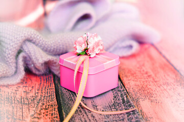 Partial blurred wooden desk table with knitted scarf and pink gift  Vintage tinted,hygge, cozy home concept.