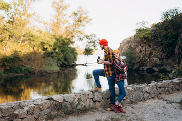Bald guy with a beard and a blonde girl in bright hats are taking pictures with an old camera