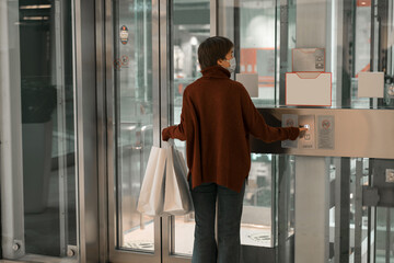 waiting elevator, holding hand shopping bags person wearing mask shopping mall. 2021 new year and christmas shopping, gift. 
against the use of plastic.