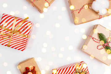 Fototapeta premium Happy New Year horizontal composition. Christmas striped design gifts box, golden and red bow, confetti glitter light on white background with copy space. Flat lay, top view