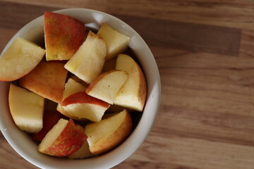 apple for breakfast. Healthy food. Apple cut into cubes and served in white pot. Apple, wooden background.