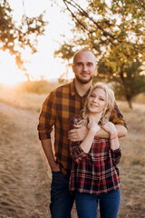 Fototapeta premium Cheerful guy with a board and a blonde girl for a walk in plaid shirts