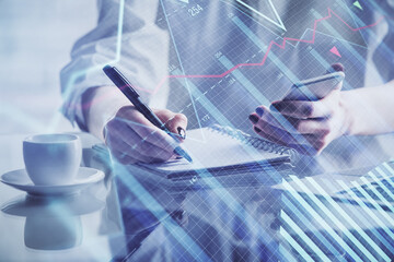 Double exposure of financial graph sketch hologram and woman holding and using a mobile device. Stock exchange concept.