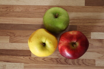 green apple, red apple and whole yellow apple on a table.
