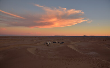 Ein Wüstenlager mit Zelten in der Wüste im Sonnenuntergang
